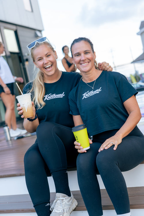Lifestyle photo featuring the Knotbound Drifter Crop Top in black at a pop up event.
