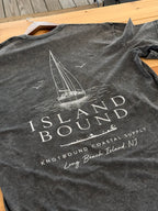 The Knotbound Island Bound Stonewash Tee laid flat on wood, showing the sailboat back graphic and Long Beach Island, NJ text.