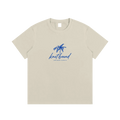 Beige t-shirt with blue palm tree design and text on a white background