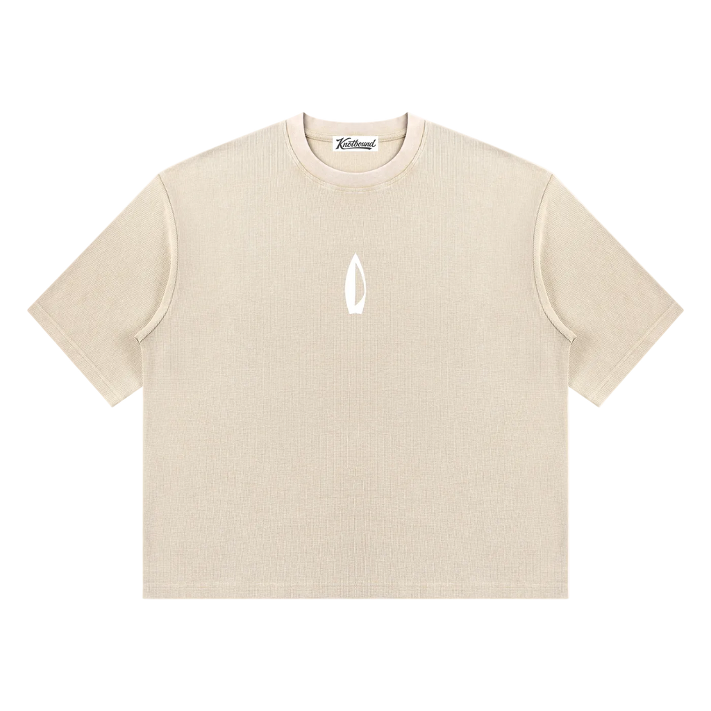 A beige short-sleeve crewneck t-shirt with a small white flame-like logo on the center chest, displayed flat against a solid white background.