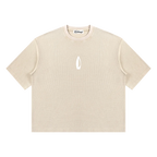 A beige short-sleeve crewneck t-shirt with a small white flame-like logo on the center chest, displayed flat against a solid white background.