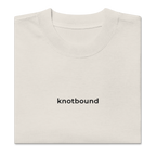 A folded off-white crewneck t-shirt with the word 'knotbound' printed in black lowercase sans-serif font on the chest, shown on a plain white background.